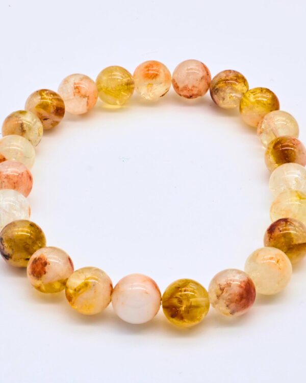 A circular beaded bracelet made of polished, round citrine gemstones featuring varying shades of pale yellow, gold, and reddish-brown, lying flat against a plain white background. Rudraksha Kavach By SnazzyWorks. Catrine Bracelet Natural